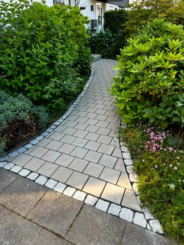 Geschwungener Gartenweg aus hellem Pflaster